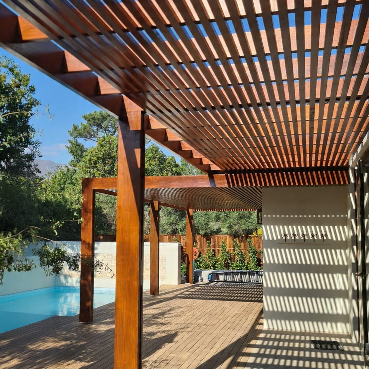 Architectural slatted pergola by Cape Town Timber Decking showing precision timber engineering and rhythmic shadow patterns.